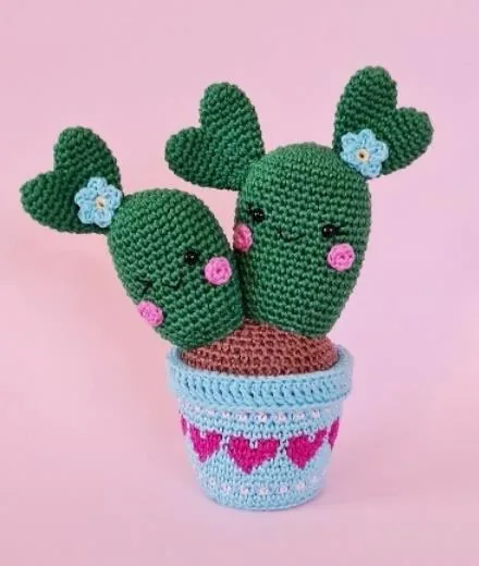 Finished twin green crochet cactus plants in a blue-rimmed pot with small flowers