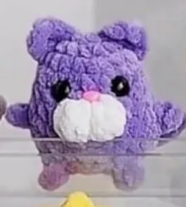 Purple miniature crochet cat with white muzzle and pointed ears